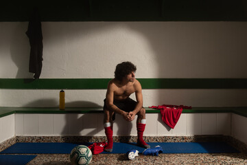 A football player in dressing room with sports uniform