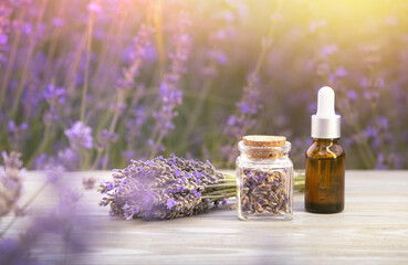 Essential lavender oil in the bottle with dropper on the gray wooden desk. Horizontal close-up.