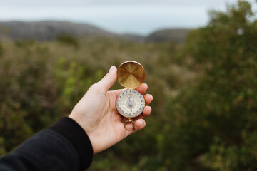 crop anonymous person tourist using compass on mountain with rough stones in daylight