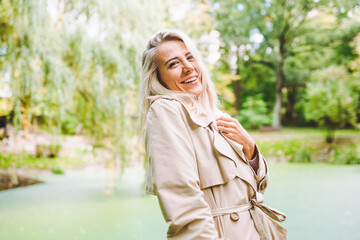 Caucasian blonde woman smiling happily on sunny summer or spring day outside walking in park.