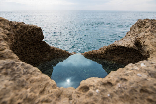 Rocky landscape of natural pool located near cave near sea on sunny day in Algar seco caves in Algarve, Portugal