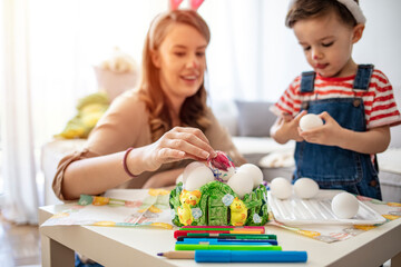 Fototapeta premium Mother and her son preparing for Easter, painting Easter eggs. Mother And Son Enjoying Creative Easter Morning, Coloring Eggs. Coloring Eggs For Easter