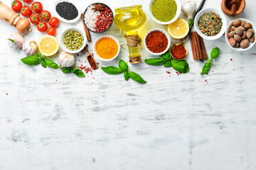 Set of Indian spices, basil and herbs on a white wooden background. Top view. Free space for text.