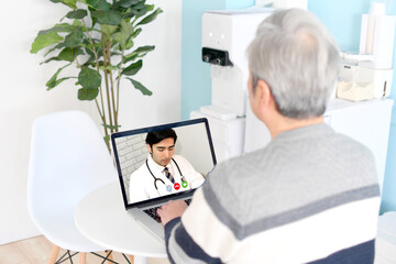 パソコンでオンライン診療を受けるシニア（高齢者）の男性
