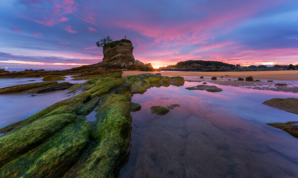 Spectacular scenery of Urros de Costa Quebrada with rough rocky formations washed by sea waves under dramatic sunset sky with dark clouds in evening time in Spain