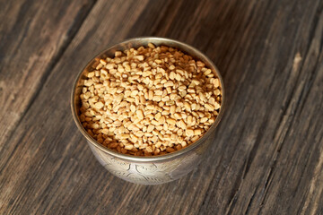 Fenugreek seeds in a bowl on a wooden table