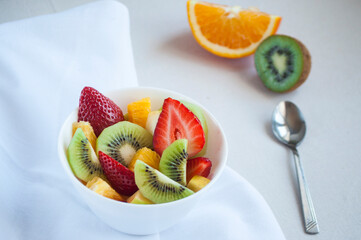 Healthy fresh delicious fruit salad with strawberries, orange, apple and kiwi. Bowl of healthy food.