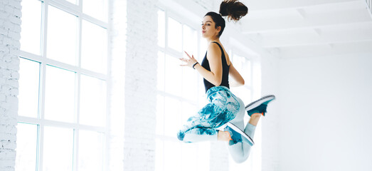 Brunette female athlete in tracksuit doing cardio exercises keeping perfect body, determined...