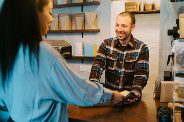 Back view a woman holding a credit card and paying at a pos