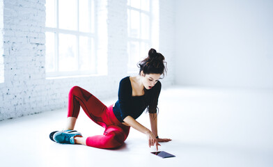 Fototapeta premium Shocked female athlete in sportive tracksuit using touch pad technology for checking online news, amazed fit girl watching online video webinar with aerobic exercises using digital tablet in gym