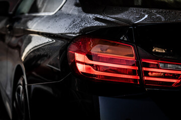A view of the rear light of a luxury black sports car.
