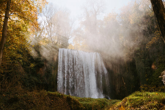 Low angle of magnificent view of waterfall in autumn woods on sunny day