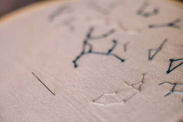 Embroidery of stars constellations weave on white fabric in hoop with sharp needle
