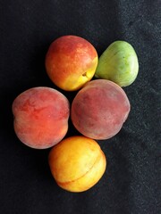 peaches nectarines and figs on a black background