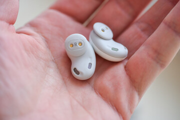 Wireless white in-ear headphones in hand, isolate