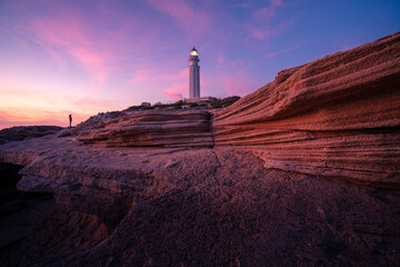 Magnificent view of lighthouse located on hill near sea against colorful sundown sky in Cadiz