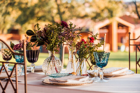 Close-up of served festive table with crystal glasses cutlery napkin on plate near bunch of fresh flowers for wedding and menu card