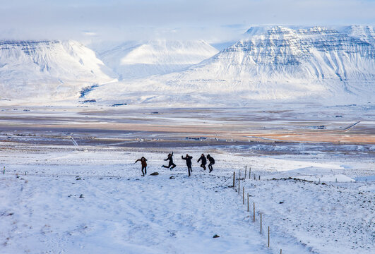 Group of travelers jumping in snowy valley while enjoying winter adventure in mountains in Iceland and having fun