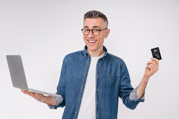 Happy mature caucasian man with credit card and laptop isolated over white background