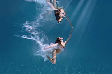Fashionable and athletic girl free diver alone in the depths of the ocean. Swimmer brunette diving...