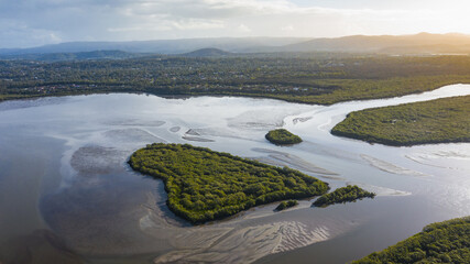 Picturesque drone view of heart shaped island covered with lush green vegetation washing by river water against sunset sky in countryside in Australia