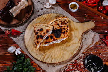 The pizza is on the kitchen table, and the ingredients are scattered around. Closed pizza pie