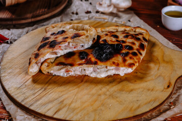 The pizza is on the kitchen table, and the ingredients are scattered around. Closed pizza pie
