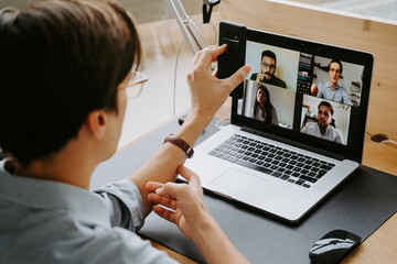 Side view male manager having video conference online via laptop while sitting at table and working from home during coronavirus epidemic