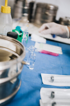 Vertical photo with the selective focus on a few glass pots with anesthesia and surgical instruments next to them on a table in a hospital operating room