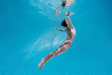 Male Caucasian man swimmer diver dancer swims under water in the sea. Summer tourism, travel...