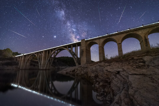 From below viaduct bridge under night sky with sparkling stars in long exposure
