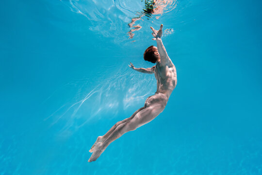 Male Caucasian man swimmer diver dancer swims under water in the sea. Summer tourism, travel journey trip voyage, holiday and vacation. Concertation, art, beauty and freedom concept