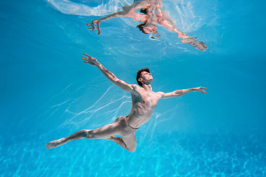 Male Caucasian man swimmer diver dancer swims under water in the sea. Summer tourism, travel journey trip voyage, holiday and vacation. Concertation, art, beauty and freedom concept