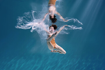 Fashionable and athletic girl free diver alone in the depths of the ocean. Swimmer brunette diving...
