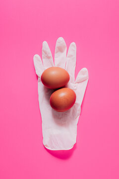 From above of similar chicken eggs on white latex glove representing organic product concept