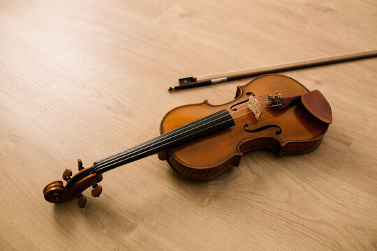 Modern acoustic violin and bow of classic design placed on wooden surface in musical studio