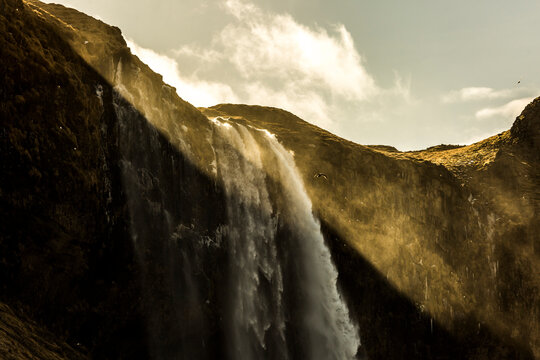 Amazing view of powerful waterfall in rocky highland terrain on sunny day in Iceland