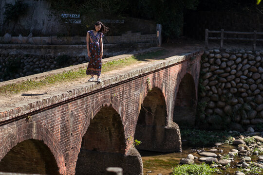 Female in maxi dress standing on Daping Red Bridge during vacation in Taiwan in summer