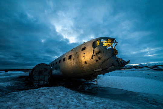 Piece of huge crashed plane in frozen lake against dark cloudy sky in Iceland