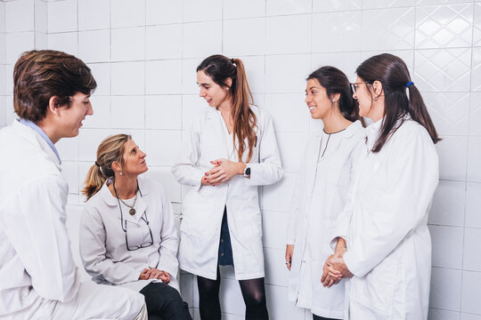 Group of doctors talking to each other with relax expression in a hospital room and dressed in white coat uniforms