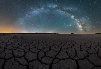 Drought cracked lifeless ground arid terrain with starry sky at night
