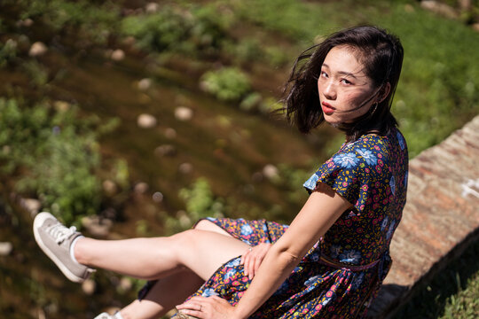 Side view of Asian female in dress sitting on old Daping Red Bridge and enjoying summer vacation in Taiwan