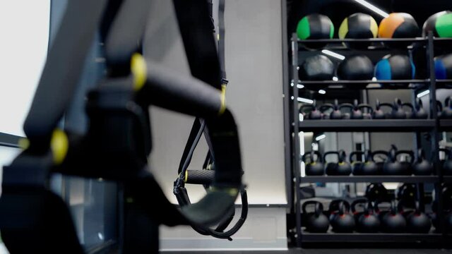 Fitness straps, kettlebells and balls in modern gym.