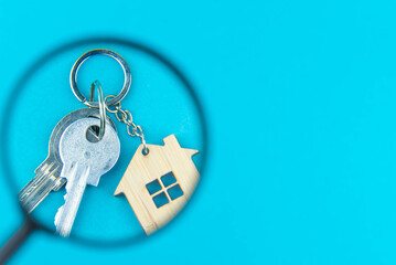 Find a home or a flat concept. Toy model house under magnifying glass. Rent apartments, Real Estate and buying a house idea. Blue background
