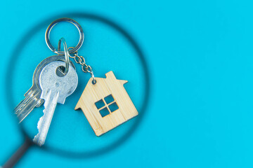 Find a home or a flat concept. Toy model house under magnifying glass. Rent apartments, Real Estate and buying a house idea. Blue background