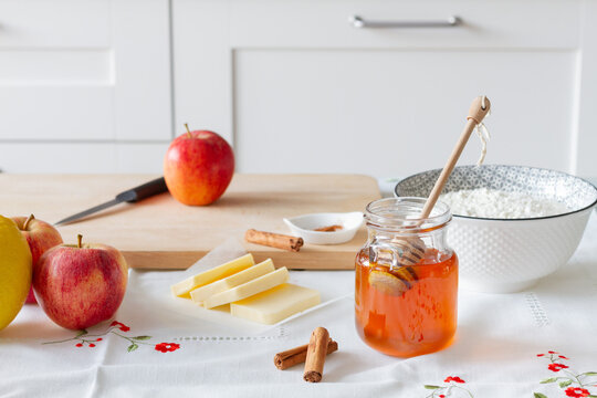 High angle of honey and butter with flour placed near cinnamon sticks and fruits for apple crumble preparation on table at home