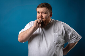 portrait of a bearded cheerful, emotional and interesting man in a white T-shirt on a blue background, showing various hand gestures. Cheerful guy show business artist, host of a glamorous show. Body 
