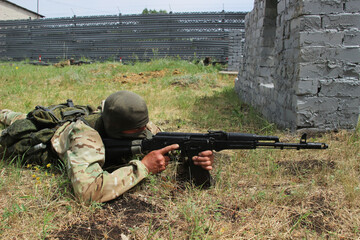 A masked military man with a Kalashnikov assault rifle in ambush