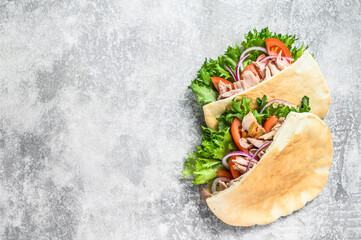 Doner kebab with grilled chicken meat and vegetables in pita bread. Gray background. Top view. Copy...