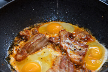 Pieces of fried meat cooked with scrambled eggs in a pan.